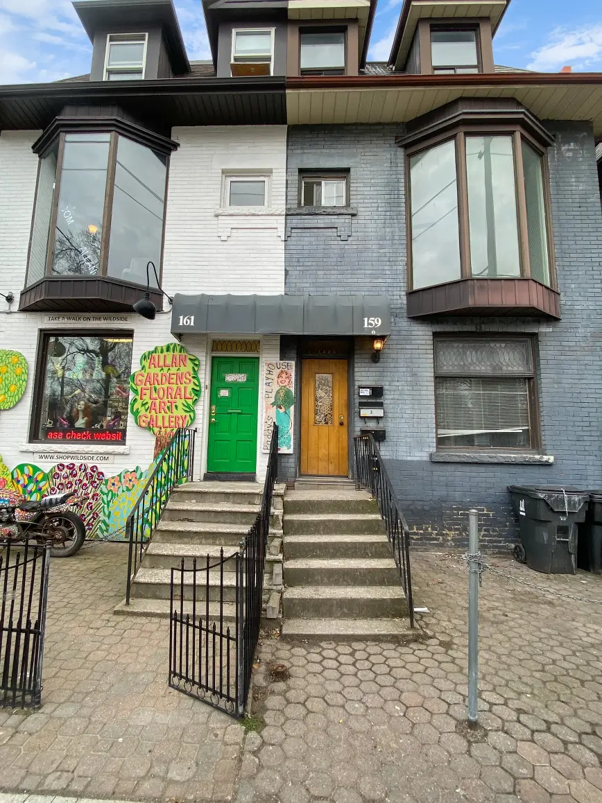 The front of 159 Gerrard Street East. The building number 159 is circled above the wooden door.