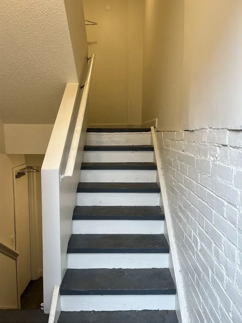 Stairs inside the building. At the landing, continue up another flight of steps.