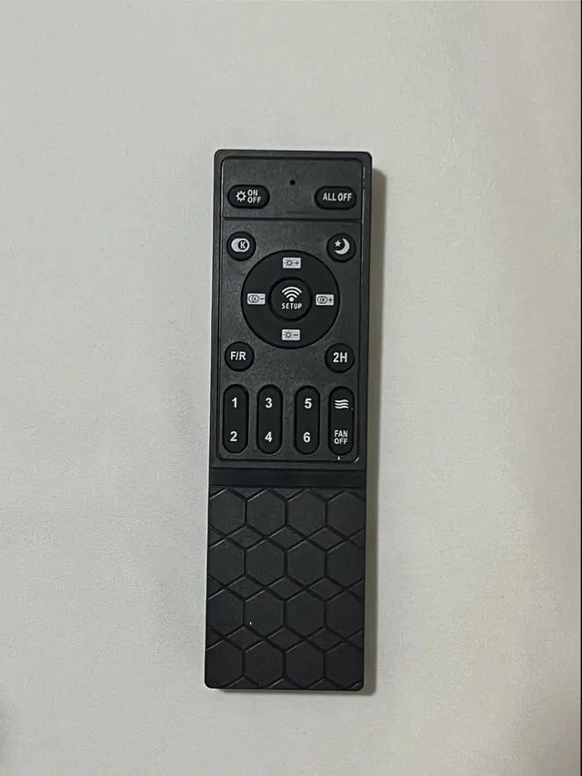 Black ceiling fan remote. The top-left button turns the light on and off. The number buttons control the fan speed.